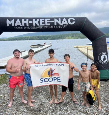 Boys holding sign in front of lake