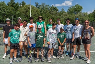 campers and staff posing for a group photo on the tennis court