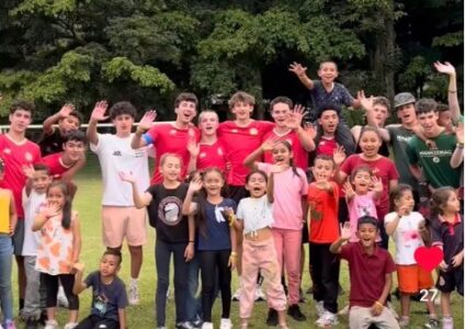 Older campers volunteering at a local camp in costa rica posing and smiling with the kids