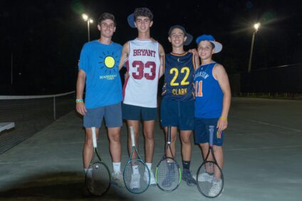 group of older campers playing tennis at night
